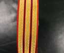 Galon lézardé or 2 bandes rouges striées noir, 27 mm large. Fabrication antérieure à 1960. Prix au mètre
