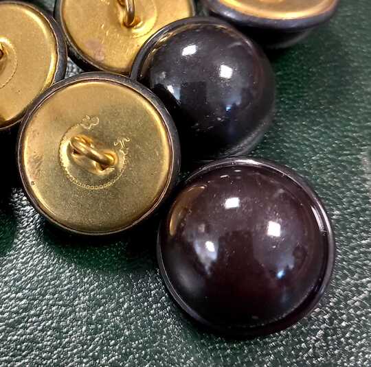 Boutons métalliques bombés à bourrelets périphériques, diam 22 mm, laqués noir. Nombre très limité.
