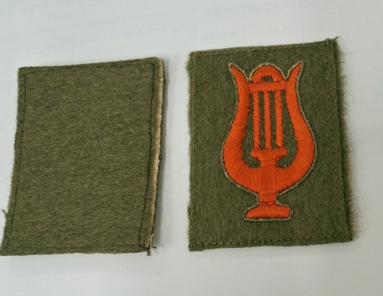 Insigne de musicien militaire: Lyre en soie rouge sur fond kaki